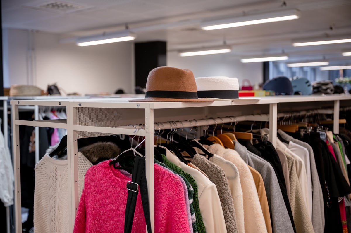 Colorful thrift store clothing rack full of sweaters and jackets
