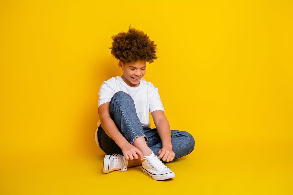Smiling young Black boy tying his sneakers